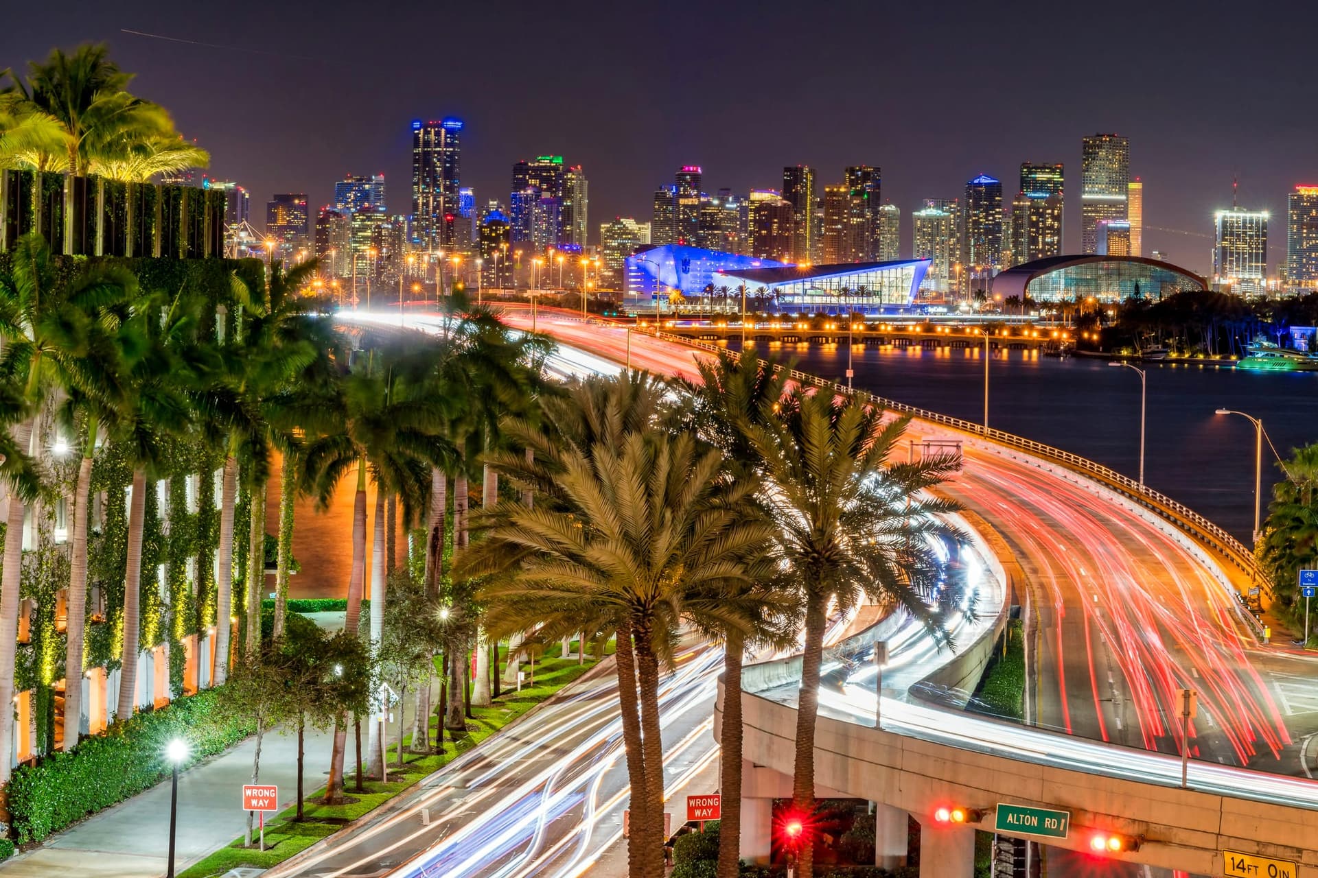 Long-exposure light trails on a South Florida causeway beneath the skyline at night